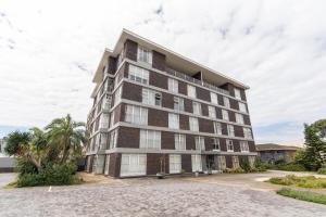 um grande edifício de tijolos com palmeiras em frente em Stylish Apartment With Park View em Port Elizabeth