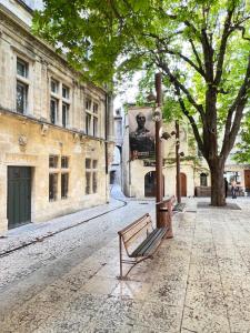 un banc sur une rue avec un arbre et des bâtiments dans l'établissement à St Rémy Petite maison au coeur du village, à Saint-Rémy-de-Provence