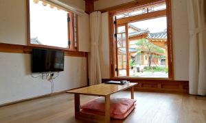 慶州的住宿－Hwangnamguan Hanok Village，客厅配有桌子和电视