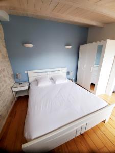 ein großes weißes Bett in einem Zimmer mit blauer Wand in der Unterkunft Les Marionnettes, Maison de ville 80m2 avec terrasse in La Rochelle