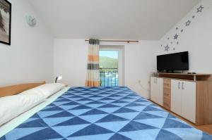 una camera con un letto blu e bianco e una TV di Apartments Lory a Rabac