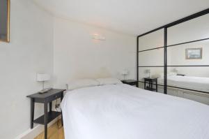 a white bedroom with a bed and a mirror at ALTIDO Charming flat overlooking River Thames in London
