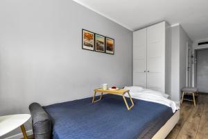 a bedroom with a blue bed and a table at Warsaw City Center Studio - Park, Subway Nearby - by Rentujemy in Warsaw