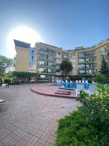 a large apartment building with a courtyard with white chairs at Studios & Apartments Perla in Sunny Beach