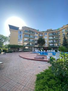 un gran edificio de apartamentos con un patio con sillas blancas en Studios & Apartments Perla, en Sunny Beach