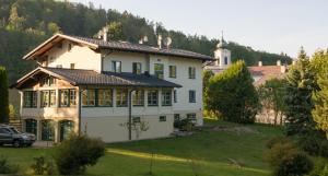 una gran casa blanca con un coche aparcado delante de ella en Dorfpension Mariahilfberg, en Gutenstein