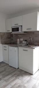 a white kitchen with white cabinets and a sink at Studio "l'aube du Perche" in La Mancelière