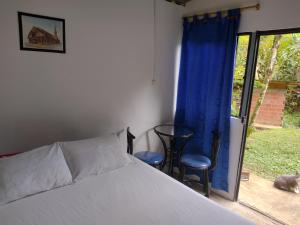 a bedroom with a bed and two chairs and a window at Sapiens house"la Gallita de roca" in Cali