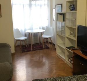 uma sala de estar com uma mesa e cadeiras brancas em Apartamento en el centro na Corunha