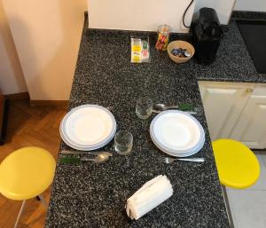 um balcão de cozinha com dois pratos brancos e duas cadeiras amarelas em Apartamento en el centro na Corunha