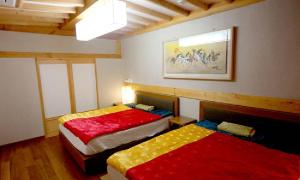 um quarto com 2 camas com lençóis vermelhos e amarelos em Hwangnamguan Hanok Village em Gyeongju