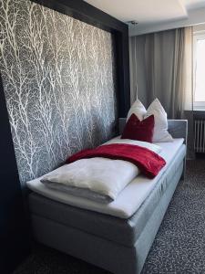 Una cama con almohadas rojas y blancas en un dormitorio en Ahorn-Zimmervermietung, en Schrobenhausen
