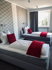 two beds in a hotel room with red pillows at Ahorn-Zimmervermietung in Schrobenhausen