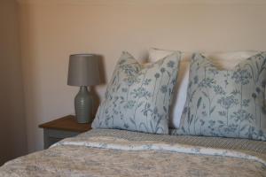 Una cama con almohadas azules y blancas y una lámpara. en Beautiful Cottage in the Heart of Stow on the Wold en Stow on the Wold