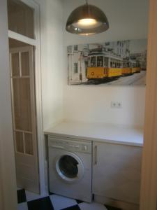 a washing machine in a room with a picture of a train at The Estrela Apartment in Lisbon