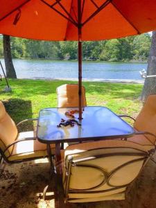 Perfect Lake Retreat في هوت سبرنغز: طاولة وكراسي تحت مظلة بجانب البحيرة