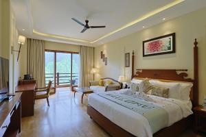 Punarnava Resort & Spa في دهرادون: غرفة نوم بسرير كبير وغرفة معيشة