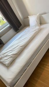 uma cama com lençóis brancos e almofadas ao lado de uma janela em U4 Spittelau TR10 em Viena