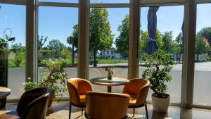 Pokój ze stołem i krzesłami oraz dużymi oknami w obiekcie Leipziger Hotel w Lipsku