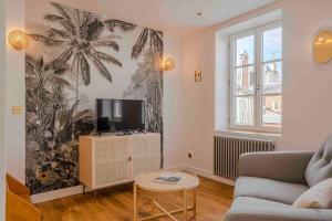 Una sala de estar con un sofá y un televisor. en Neptune, en Trouville-sur-Mer
