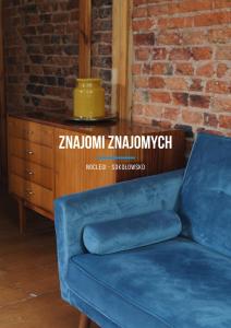 a blue couch in a room with a brick wall at Znajomi Znajomych in Sokołowsko