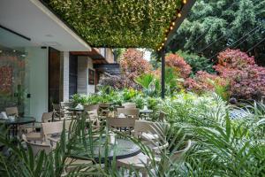 un patio al aire libre con mesas, sillas y plantas en First Class Hotel by 5 Host, en Medellín