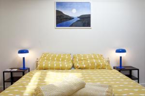 a bedroom with a yellow bed with two blue lamps at Le St Apollinaire n°3 - Ma Cabotte in Meximieux
