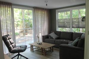 a living room with a couch and a table and windows at Kellux vakantiewoning - Heleen in Mariënberg