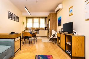 a living room with a television and a dining room at The Plovdiv Pad: Your 1-BD Hideaway in the Center in Plovdiv