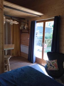 um quarto com uma cama e uma porta de vidro deslizante em Chalet grenouille Domaine de la Mamounette em Champclause