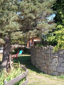 a stone wall and a tree and a bench at Chalet grenouille Domaine de la Mamounette in Champclause