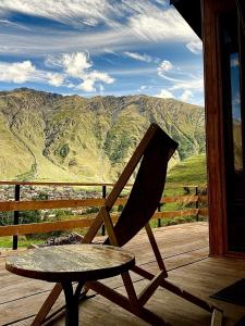 a chair sitting on a porch with a view of mountains at Little Wood House Gergeti in Stepantsminda