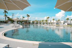 ein Pool in einem Resort mit Sonnenschirmen in der Unterkunft Adamas Resort & Hotel in Lezha