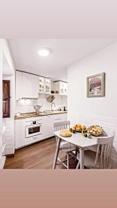 a white kitchen with a table and a table and chairs at La casa de mis suegros in Candeleda