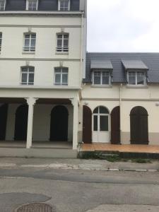 een wit huis met bruine deuren en een straat bij Nouveau! Superbe appartement avec terrasse vue mer in Ambleteuse