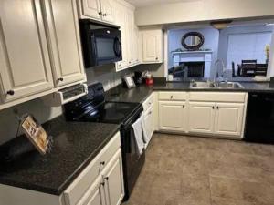 a kitchen with white cabinets and black counter tops at Elis Woodland Escape in Russellville