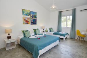 a bedroom with two beds and a table and a chair at Rodrigues Holiday Family Villa Zourit in Rodrigues Island