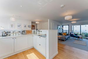Una cocina con gabinetes blancos y una sala de estar. en 2 Bed Ground Floor Apartment - 11 Plas, en Pistyll