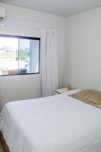 um quarto com uma cama branca e uma janela em Prox ao hospital HRT e Anchieta e faculdade - wifi- netflix - ar-condicionado em Taguatinga