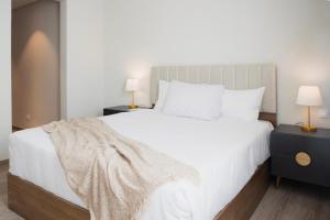 una camera con un grande letto bianco e due lampade di Mivida Emaar - Residence by Elegant Hospitality a New cairo
