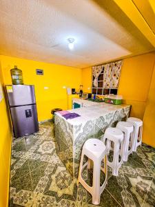 a kitchen with yellow walls and a counter with stools at Posada Hostel Adri in Providencia