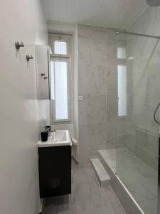 ein weißes Bad mit einem Waschbecken und einer Dusche in der Unterkunft Charmant T1 climatisé en centre ville / Paradis in Marseille