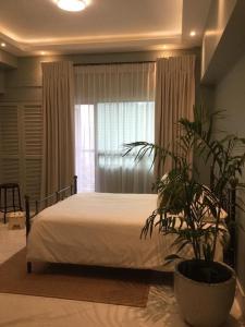 una camera da letto con un letto e una pianta di fronte a una finestra di Condo Hotel at Greenbelt makati with cityview a Manila