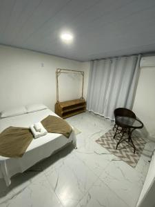 a bedroom with a bed and a chair and a table at Pousada Lisamar in Mangaratiba