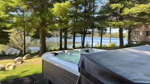 a hot tub in a backyard with a view of the water at Chalet le Huard directement au bord du lac in Saint Zenon