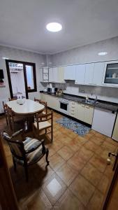 - une cuisine avec une table, une table et des chaises dans l'établissement Amodiño,casa alquiler vacacional, à Viveiro