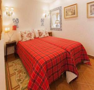 a bedroom with a red bed with a red plaid blanket at Villa Estefânia em Sintra in Sintra