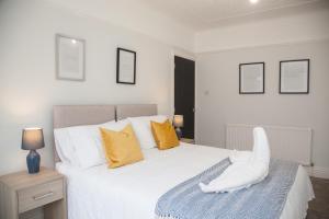 una camera da letto con un grande letto bianco con cuscini gialli di 8 Karslake Road a Wallasey