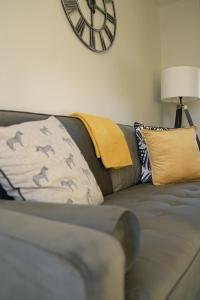 a living room with a couch with a clock on the wall at McCracken House in Uddingston