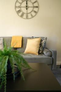 un orologio sul muro sopra un divano con cuscini di McCracken House a Uddingston